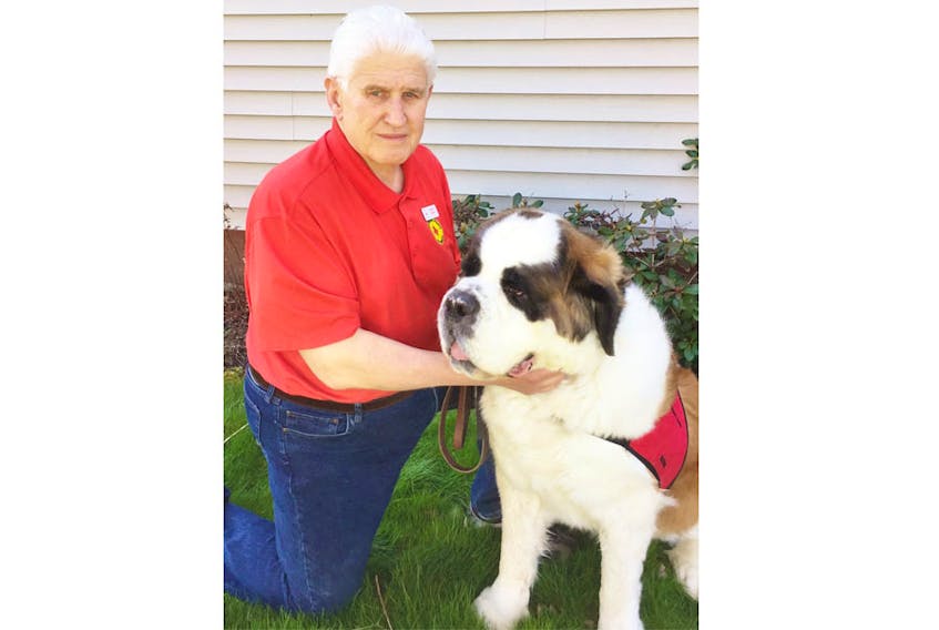 Therapeutic Paws of Canada (TPoC) volunteers Mark Grant, Halifax team leader, and Saint Bernard Watson pause from their busy visitation schedule to pose for a photo.