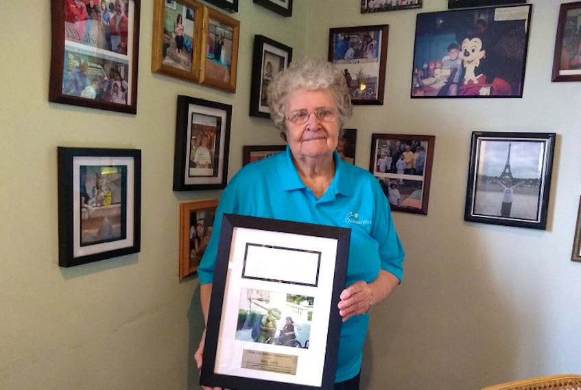 Betty Hebb is shown with the Laura Cole National Volunteer Award she received in 2017 for her years of fundraising for the Children's Wish Foundation. Behind her on the wall of the Farmer's Family Diner are photos of her 'wish children.'