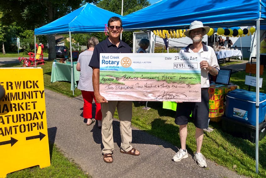 John H. Smith, left, of the Mud Creek Rotary presents Berwick Community Market manager Chris Goddard with a cheque for just over $2,300 as part of the market's first anniversary celebration July 27. The funding will go toward purchasing canopies to allow for outdoor vendor spaces.