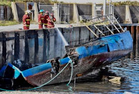 Members of the Little Brook Volunteer Fire Department train water on the charred remains of a boat that was reported to be on fire the morning of Oct. 5. The boat belongs to a member of the Sipekne’katik First Nation. The RCMP is investigating the fire. TINA COMEAU PHOTO 