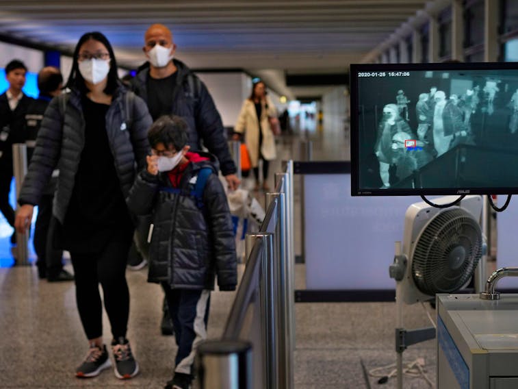  A health surveillance officer uses a temperature scanner to monitor passengers arriving at Hong Kong International Airport on Saturday, Jan. 25, 2020.