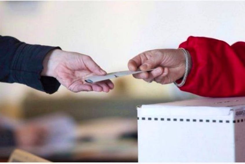 An election worker hands a ballot to a voter.