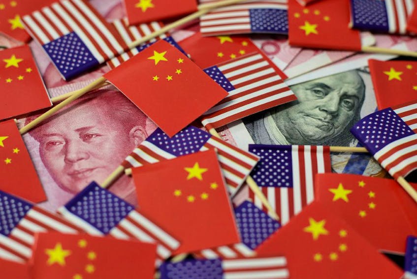A U.S. dollar banknote featuring American founding father Benjamin Franklin and a China's yuan banknote featuring late Chinese chairman Mao Zedong are seen among U.S. and Chinese flags.