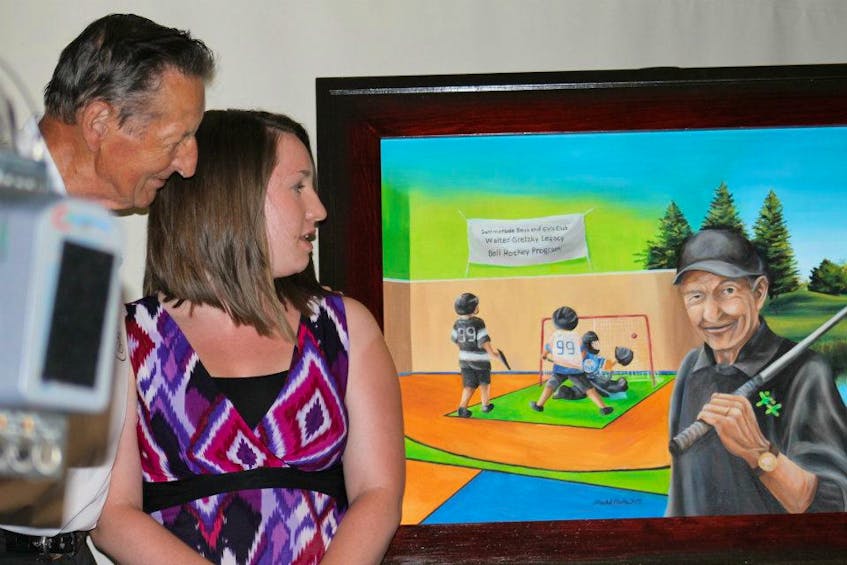 Former Summerside Boys and Girls Club employee Rachel Carter and Walter Gretzky check out the painting that was unveiled during the club’s annual celebrity dinner gala as part of the celebrity golf tournament. Carter painted the image for the club’s naming of the Walter Gretzky Legacy Ball Hockey Program.
