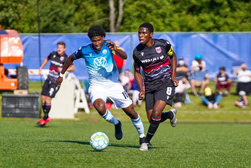 HFX Wanderers FC captain Andre Rampersad, left, and Cavalry FC's Elijah Adekugbe chase the ball during Saturday's Canadian Premier League game in Charlottetown. (CANADIAN PREMIER LEAGUE)

