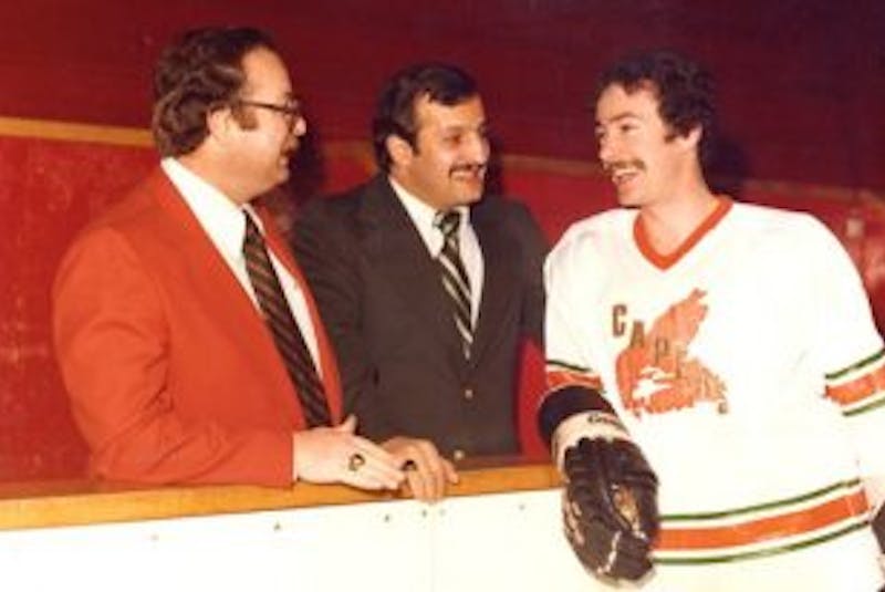 ['From left, University College of Cape Breton Capers head coach Carl (Bucky) Buchanan and assistant coach Paul Hanna talk with Capers forward Mike Peck during a Capers practice after winning the 1977-78 Canadian Colleges Athletic Association men’s hockey championship. Both Buchanan and Hanna are wearing their championship rings.']