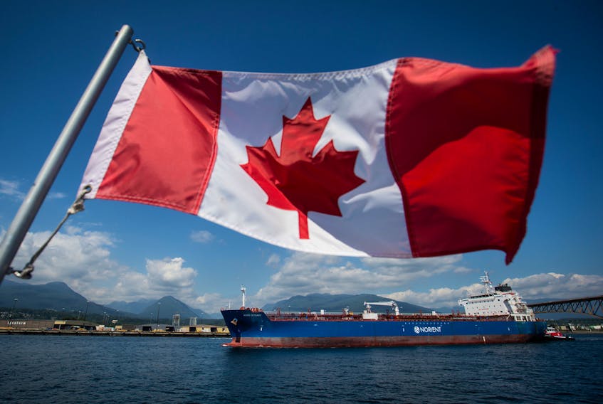 A Canadian flag flies from a Harbour Authority patrol boat as the Nord Steady oil and chemical tanker is guided by tugboats out of the Port of Vancouver in Vancouver, British Columbia, July 11, 2017.