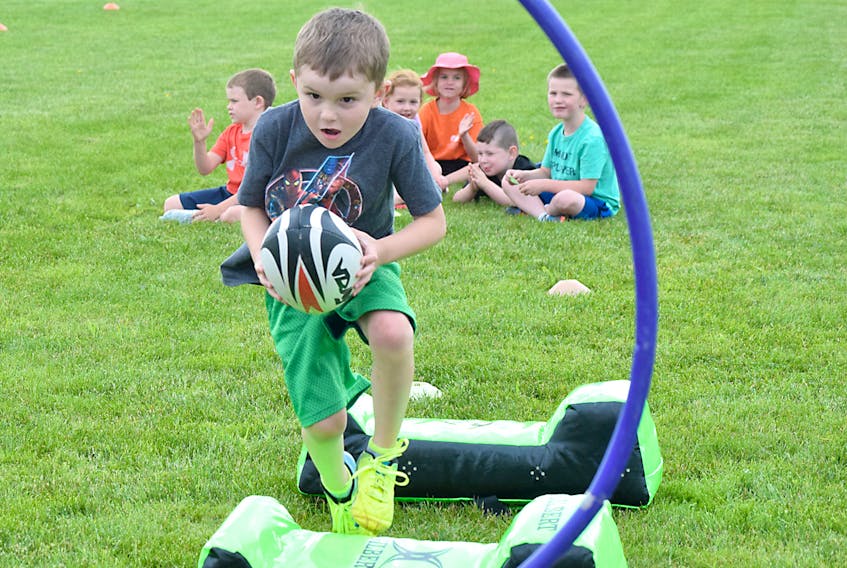 Etine MacKay takes the ball over the pads and towards the hoop during a drill on Tuesday at the Timbits rugby camp at the Truro Saints Rugby Park. More than 50 youngsters are registered for the camp, which runs until Aug. 20.