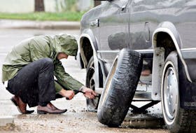 A man changes a flat tire on a rainy day in Edmonton. Jason Franson/Postmedia News files