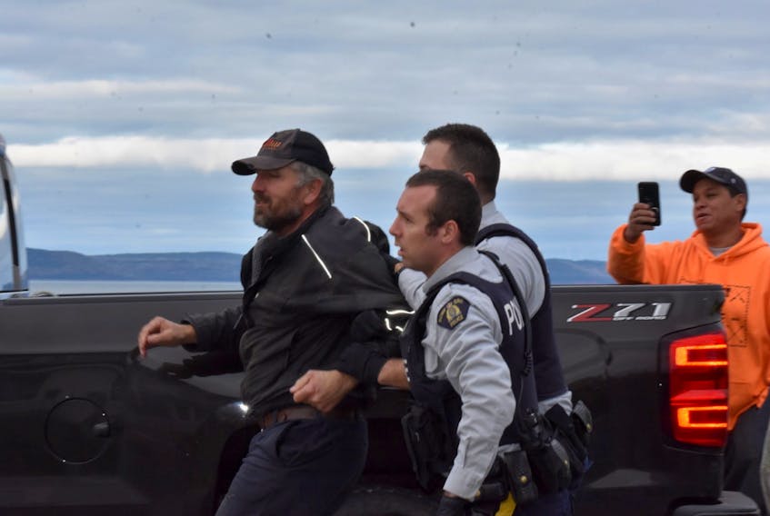 RCMP escort a man away from a confrontation over the moderate livelihood fishery on St. Mary's Bay.