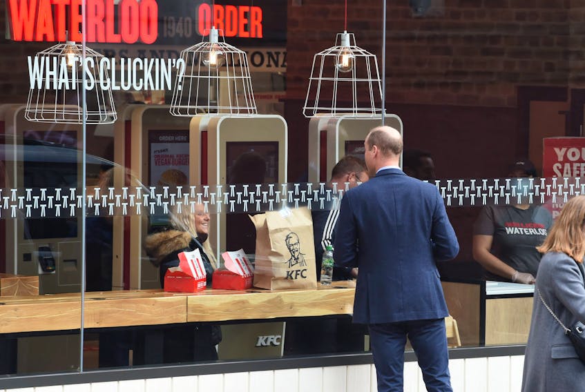 Prince William, Duke of Cambridge speaks to a member of the public through the window of a KFC restaurant before attending the launch of the Hold Still campaign at Waterloo Station.