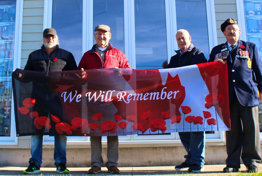 North Sydney Historical Society board members Bill Weatherbee, from left, Wes Stewart, Joe Meaney and Harry Taylor hold a special Remembrance Day banner outside the society’s museum on Commercial Street in North Sydney. With COVID-19 reducing Nov. 11 ceremonies to largely ceremonial events, the museum’s downtown window display honouring area veterans has taken on added meaning. Chris Connors/Cape Breton Post