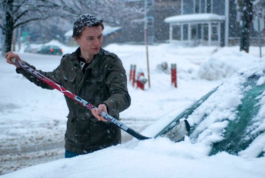 Holland College student Ross MacNeill uses a hockey stick to clear off his car in this file photo. The Weather Network predicts fewer big winter storms for P.E.I. over the next few months. Guardian photo by Mitch MacDonald