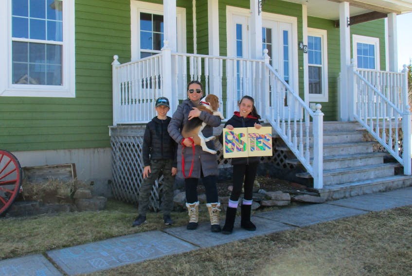 Petra LeBlanc (centre) and her children, Jacob (10) and Petra (12) take a photo outside their Baddeck home with their Easter beagle Maple. Their neighbourhood has been holding an Easter egg hunt for 10 years and LeBlanc didn't want their tradition to end because of the emergency measures in place in Nova Scotia to limit the spread of COVID-19. So she came up with the idea of a word hunt instead - families will make signs like the one her daughter is holding and hide them on their lawns and windows instead of the eggs. CONTRIBUTED 