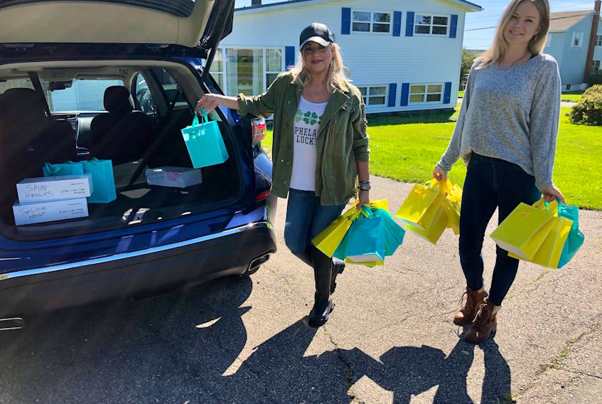 Erin MacDonald, left, and Vanessa Walker pack the trunk of MacDonald's car with packages of sexual health products like condoms, dental dams and menstrual cups, which they were delivering to 48 places from Eskasoni to Glace Bay on Sept. 25. Walker, who works for the Cape Breton Centre for Sexual Health, said they closed their office and are working remotely so she put a post on Facebook about having these products available. The sexual educator said within two hours, all the Diva Cup menstrual products were gone. "(With no physical office) I had to get creative with how to get safe sex supplies out there," said Walker, who also packed safer sex books in some packages. Walker said it's thanks to partners like Friendly Divas in Halifax who donate the menstrual cups the centre is able to provide products like these for free. To find out more about their sexual health packages and other services, email cbcforsexualhealth@gmail.com or find them on Facebook. NICOLE SULLIVAN/CAPE BRETON POST 