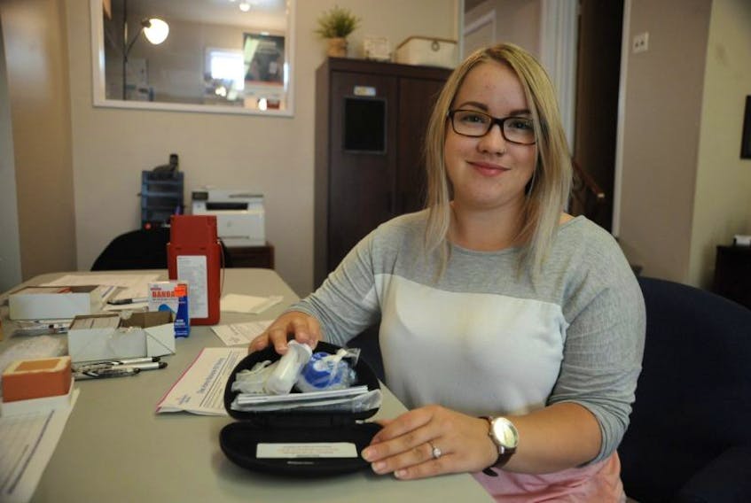 Jessica Hackett of the AIDS Committee of Newfoundland and Labrador poses for a photo with one of the naloxone kits the organization was handing out free of charge in Corner Brook Thursday.