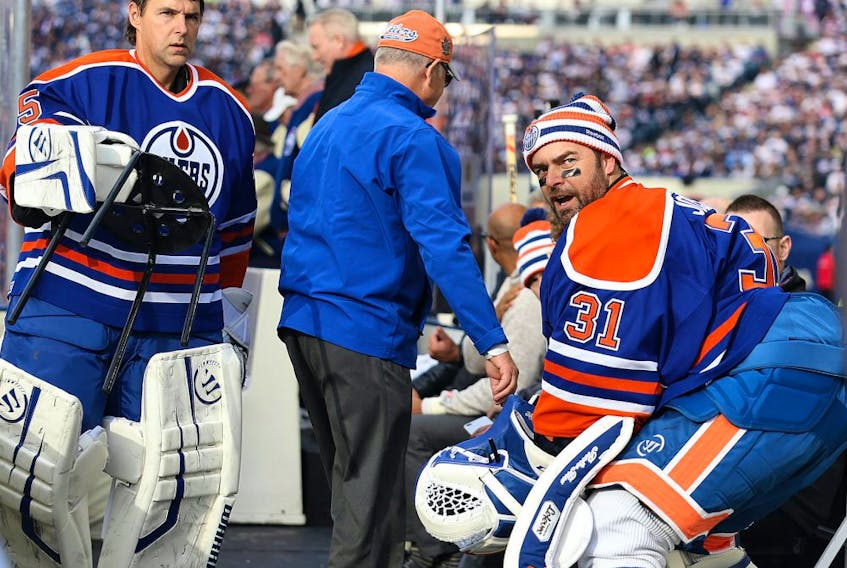 Edmonton Oilers goaltender Dwayne Roloson (left) and Curtis Joseph find their seats at the start of the Heritage Classic alumni game in Winnipeg on Sat., Oct. 22, 2016.
