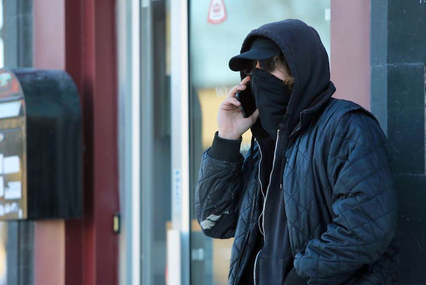 A man wearing a gaitor-style mask talks on his cellphone outside a shop on Sherbrook Street in Winnipeg on Mon., Jan. 4, 2021. Kevin King/Winnipeg Sun/Postmedia Network