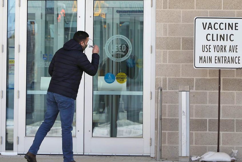 A man checks to see if he has the right doors near the COVID-19 vaccination super-site at the Winnipeg Convention Centre in Winnipeg on Sunday, Feb. 28, 2021. 