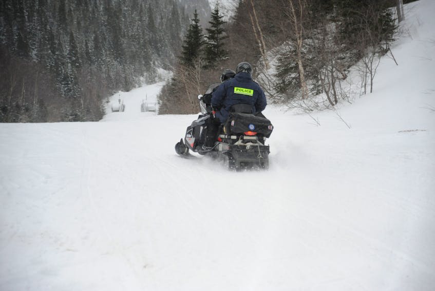 Sgt. Eric Humber of the RCMP hitches a ride with Darren Williams, co-ordinator of the Deer Lake Search and Rescue team, as they head out on the trail to join searchers looking for a missing snowmobiler in the Jackson’s Arm area Monday.