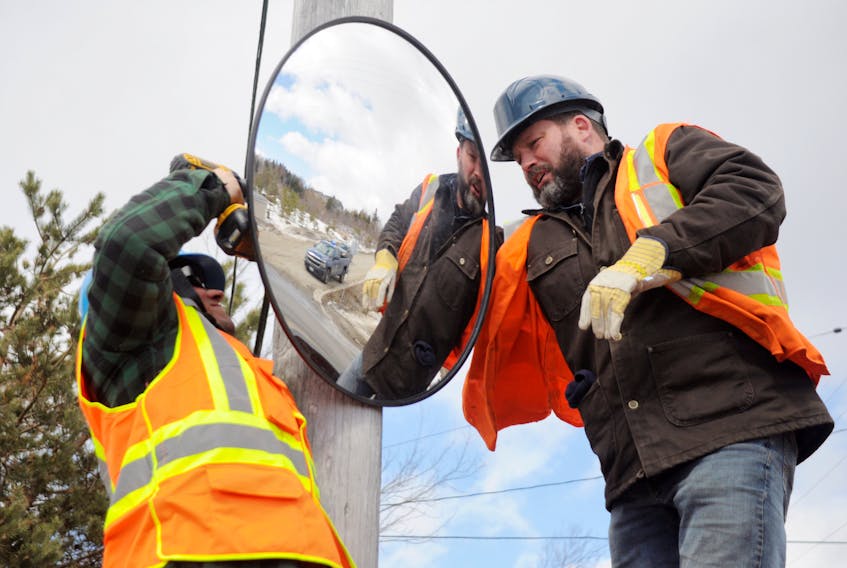 Perry LeCointre, left, and Mark Byrne, public works employees with the Town of Stephenville, are seen installing a traffic mirror on a utility pole on Brook Street across from the intersection with Ridgeview Avenue.