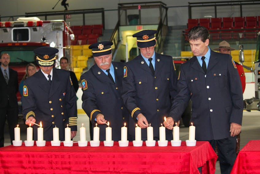 Fire Chief Wayne Reilly, left, of the Stephenville Fire Department and his three captains from left: Don Gibbon, Chris Butt and Tony Pottle light candles in honour of those who lost their life in the tragedy of Sept. 11 and local member of their fire department who have died.