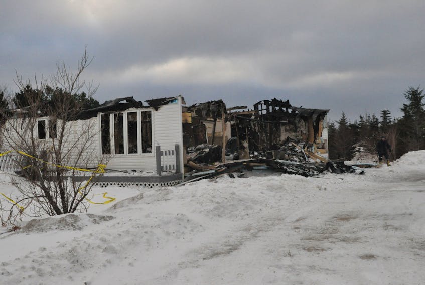 A police officer is seen at right taking photos of a home on Main Street in Port au Port East that was completed destroyed in a fire on Wednesday evening.