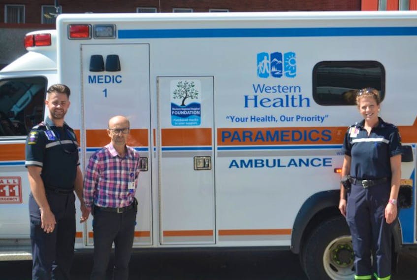 (From left) Primary Care Paramedic Matt Gallant, Regional Director of Paramedicine and Medical Transport David Buckle, and Advanced Care Paramedic Heather Williams pose in front of Western Health’s new ambulance on Monday.