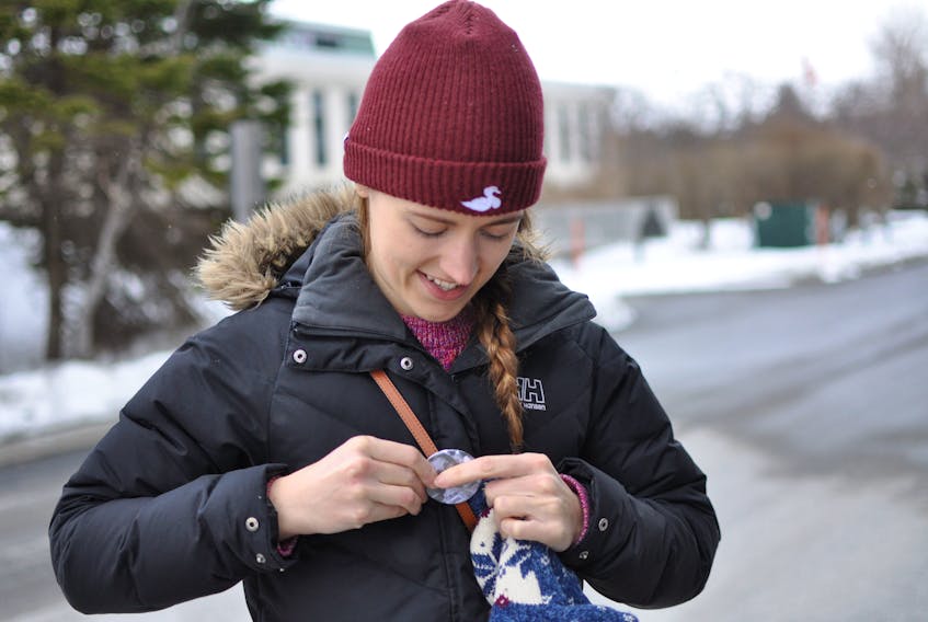 Amy Powell pins a Rehtaeh Parsons button to her jacket prior to the start of a walk in memory of the Nova Scotia teen in Corner Brook on Saturday. Parsons, who died in 2013, had been the victim of online bullying and harassment after being allegedly raped by four boys two years before.