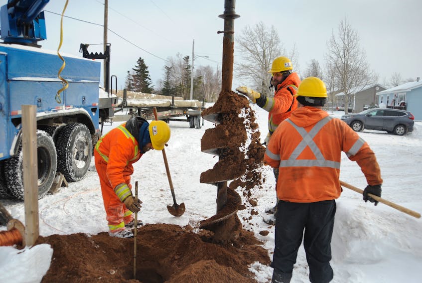 As clearly seen by this drill bit being cleaned by a crew installing new utility poles on Pine Tree Drive in Deer Lake, the ground underneath the riverside road is essentially beach sand.