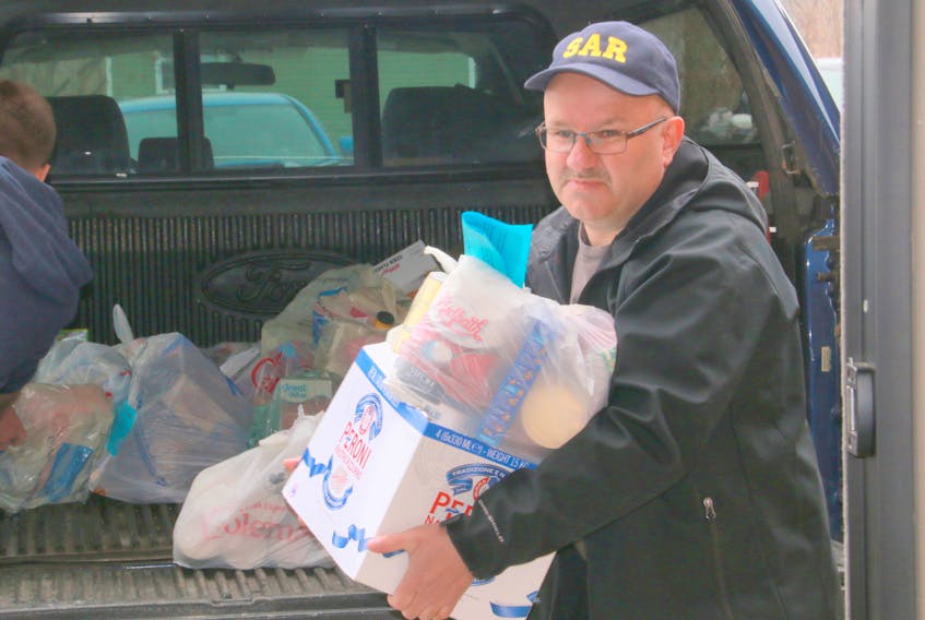 Here, Dean Jenkins, a member of Deer Lake Search and Rescue, poses for a photo while helping unload a pickup truck full of food donations picked up by fellow search and rescue members.