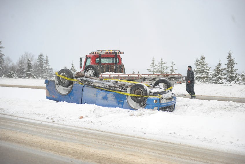 A tow truck driver with Conway’s Towing sizes up the best way to right and remove this flipped Ford F150 pickup truck from the median of the Trans-Canada Highway between the Lewin Parkway and Riverside Drive intersections in Corner Brook Thursday afternoon.
