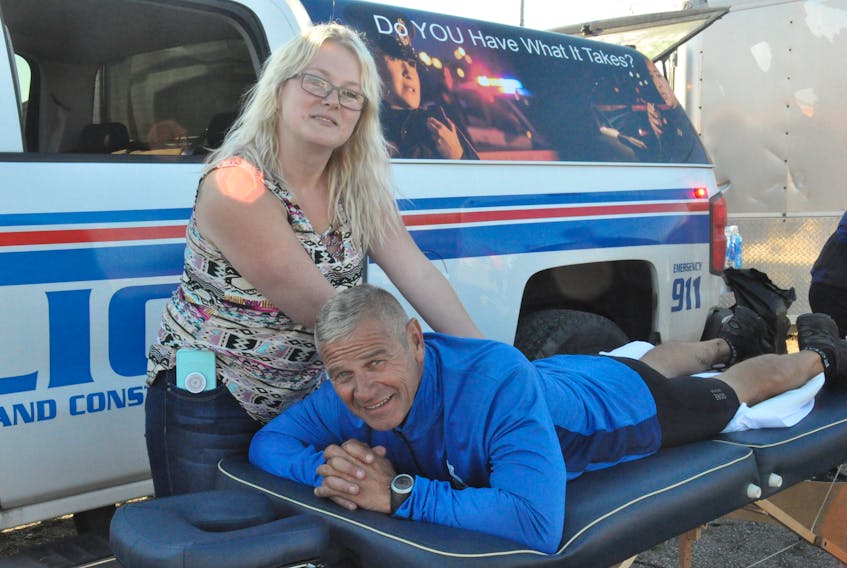 After a cycle run from Port aux Basques on Thursday morning, Sgt. Ken Jackson of the RNC in St. John's poses for a photo while getting some kinks out with much needed massage therapy from Samantha LaCosta, a massage therapist in Stephenville, during a stop and fundraiser in Stephenville Thursday afternoon.