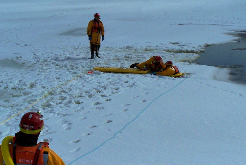 Grant Curnew, foreground, and Walter Shoefer, standing at far right, look on as Shawn Hynes pulls a rescue board toward him to help Janet Fradsham out of the icy waters of Noel's Pond in Stephenville during training by members of the Stephenville Kippens Port au Port Search and Rescue team on Sunday. Members of the team continually train to upgrade their skills and knowledge in the many disciplines of their volunteer work. Like many other responders, these volunteers spend many hours training.