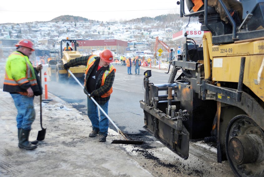 Ray Leonard, right, rakes asphalt, while co-worker Perry Cross stands by with a shovel as their crew from Marine Contractors paves the eastern approach to the new Main Street bridge in downtown Corner Brook Tuesday afternoon.