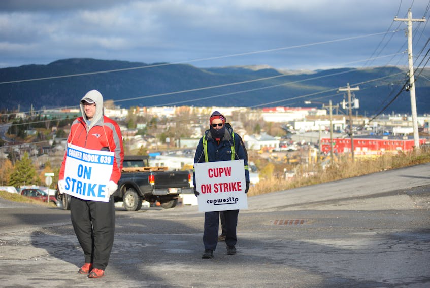 Canada Post workers Brent Mahoney, left, and Darrell Vincent walk the picket line outside the depot on Maple Valley Road in Corner Brook Monday as their union, Local 039, took its turn participating in rotating strikes by the Canadian Union of Postal Workers.