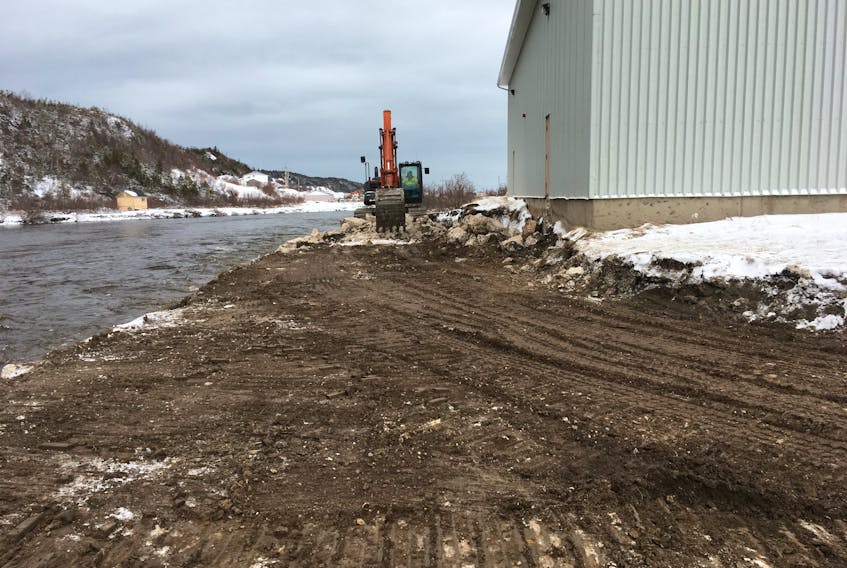 Crews work feverishly to rebuild the eroding riverbank behind Jakeman All-Grade School in Trout River in this photo taken Tuesday.