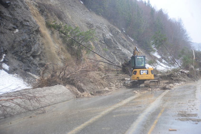 A backhoe works to clear landslide debris from Route 450 on the south shore of the Bay of Islands between Halfway Point and Benoit's Cove last Saturday morning. This issue would turn out to be the least of the problems with the road.