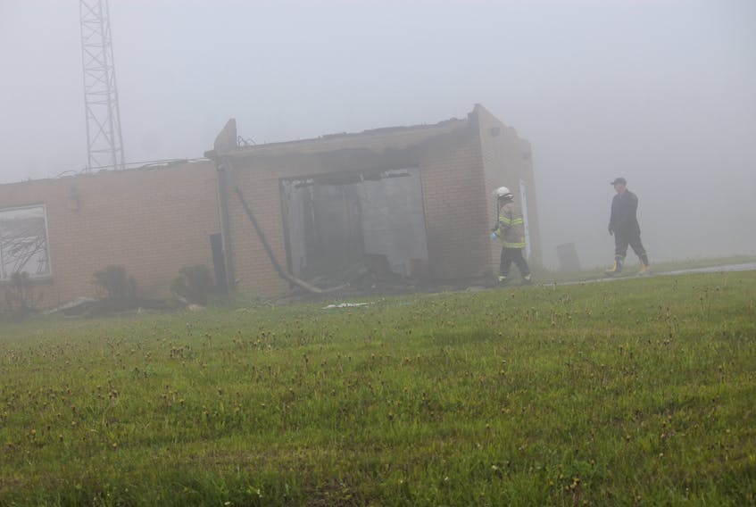 Despite foggy conditions late Tuesday morning, a Lourdes firefighter is seen assisting a fire investigator in the former RCMP Building in Piccadilly that was destroyed on Monday.