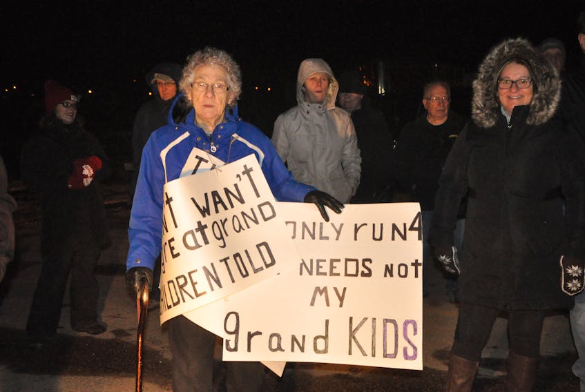 Daphne Russell carried three signs expressing her opposition to having a crematorium located on Main Street in Deer Lake during a protest outside the town hall on Monday night.