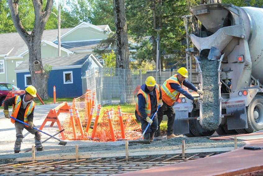 A crew spreads concrete on the new traffic island at the intersection of West Valley Road, Central Street and Park Street Tuesday afternoon. Pathways of coloured cement have already been poured on the island.