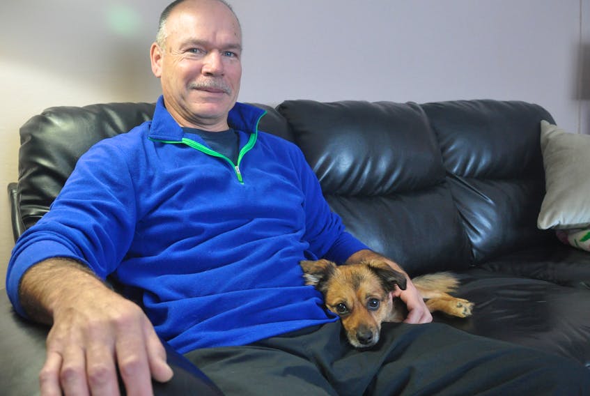 Gary White sits on the couch with his dog Toby.