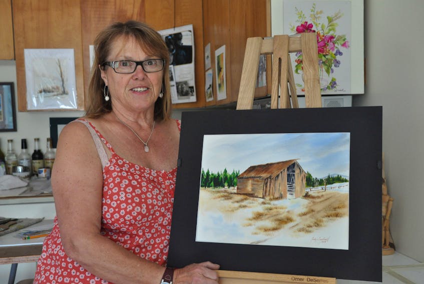 Judy Cantwell displays her water colour painting of a log barn, which was the property of Philip Gabriel and his great grandfather from 1941-42. It's one of 42 depictions of buildings taken from photos featured in "Back of the Pond" book.