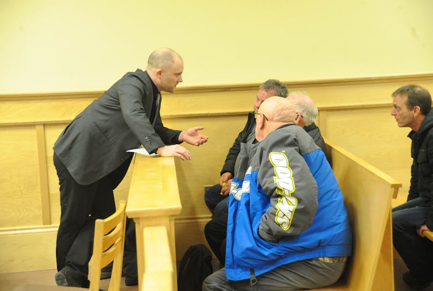 Defence lawyer Robby Ash, left, talks to the defendants in the fisheries court case involving harvesters based in Woody Point, including Todd Young of 3T’s Limited, second from left, during proceedings at provincial court in Corner Brook Thursday.