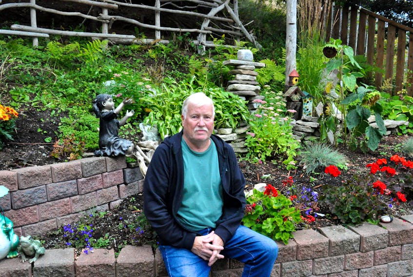 Lloyd Pretty, the artist who is now an author, poses for a photo in his flower garden just outside his painting studio in Stephenville.