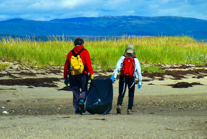 Volunteers carry garbage collected during a previous beach cleanup on Sandy Point in St. George's Bay.