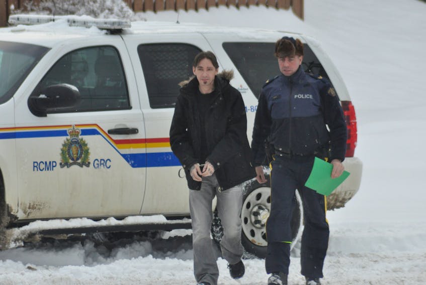 An RCMP officer leads Justin Wrathall, a Stephenville man charged in connection with an armed robbery at a gas bar in Stephenville on Jan. 3, 2017, into Stephenville Provincial Court on Thursday.