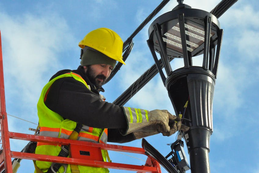 Matt Dollard, an employee of EFCO Enterprises, is seen installing a new street light head on Main Street in Stephenville.