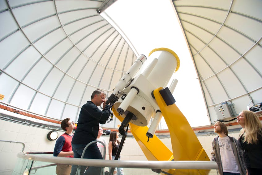 Dr. Aleksandrs Aleksejevs, physics, operates the astronomical telescope in the Grenfell Campus Observatory as Dr. Svetlana Barkanova, physics, and students look on.