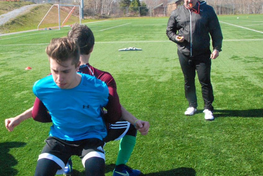 Coach Jeff Mitchell keeps a close eye on two of his players doing a strength exercise during a recent practice session for the Western Wolves U17 male soccer team competing in the provincial U17 male soccer league this summer.